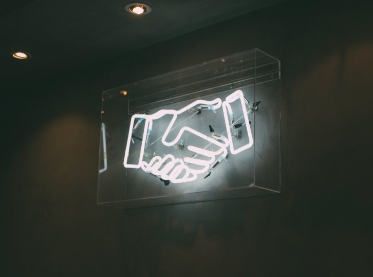 a neon sign of two hands shaking in agreement